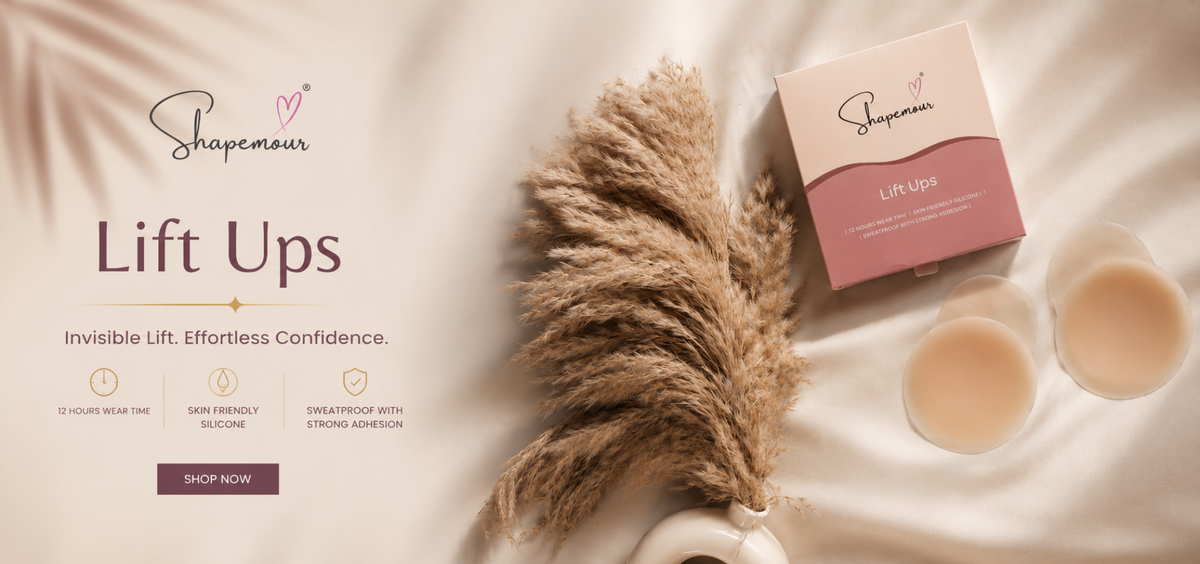 Shapemour Lift Ups breast augmentation kit shown on a beige fabric background with decorative pampas grass, two silicone cups, and the product box.